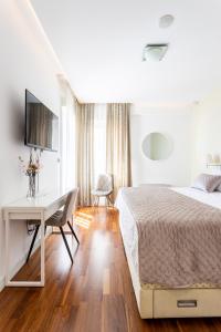 a white bedroom with a bed and a desk at Apartments Blue Maris Žnjan in Split