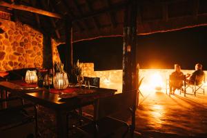 a couple sitting at a table in front of a fire at Makongo Hills Lodge in Magudu