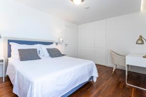 a white bedroom with a white bed and a desk at Apartments Blue Maris Žnjan in Split