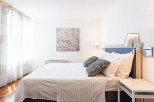 a bedroom with a bed with white sheets and pillows at Apartments Blue Maris Žnjan in Split
