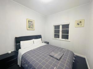 1 dormitorio con 1 cama con manta azul y blanca en Amber Hill A en Pukekohe East