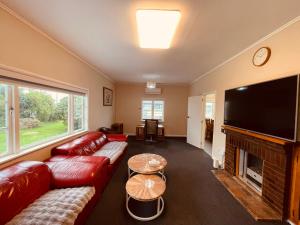 uma sala de estar com um sofá vermelho e uma televisão de ecrã plano em Amber Hill A em Pukekohe East
