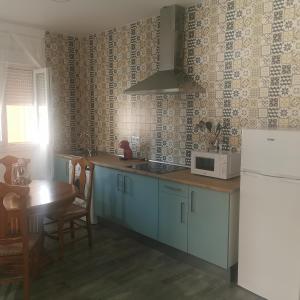 cocina con armarios azules, mesa y microondas en Apartamentos Sanlucar Beach 1 en Sanlúcar de Barrameda