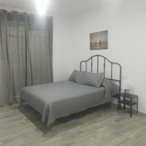 1 dormitorio con 1 cama, 1 mesa y 1 foto en Apartamentos Sanlucar Beach 1 en Sanlúcar de Barrameda