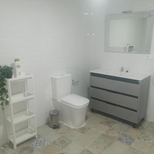 y baño con aseo blanco y lavamanos. en Apartamentos Sanlucar Beach 1 en Sanlúcar de Barrameda