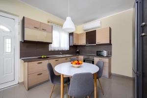 une cuisine avec une table avec des chaises et un bol de fruits dessus dans l'établissement Sunny Garden Apartments, à Pastida