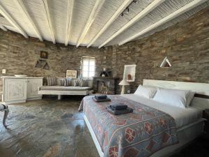 1 dormitorio con 1 cama grande y pared de piedra en The Stone Windmill, en Koundouros