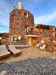 un edificio de piedra con sillas y un molino de viento en The Stone Windmill, en Koundouros