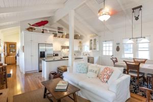 a living room with a white couch and a kitchen at Sunshine Cottage just steps to Kailua beach in Kailua