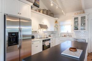 a kitchen with white cabinets and a stainless steel refrigerator at Sunshine Cottage just steps to Kailua beach in Kailua