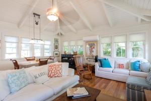 a living room with two white couches and a table at Sunshine Cottage just steps to Kailua beach in Kailua
