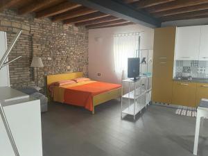 a bedroom with a bed and a tv and a brick wall at Casa Fabbro in Palazzolo dello Stella
