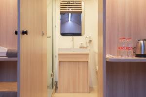 a bathroom with a sink and a mirror and a television at Bobocabin Ranca Upas, Bandung in Bandung