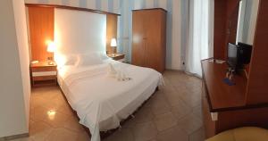 ポルトパーロにあるHotel Vittorioのベッドルーム(白いシーツ付きのベッド、テレビ付)