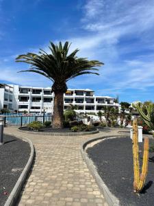 a palm tree in front of a large building at Blue Ocean in Costa Teguise