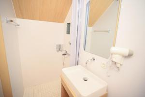 a white bathroom with a sink and a shower at Bobocabin Kaldera, Toba in Parmonangan