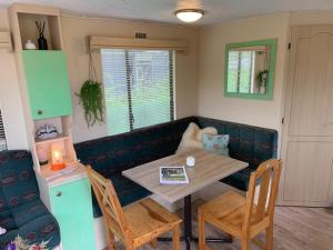 ein Wohnzimmer mit Tisch und Stühlen und einer Couch in der Unterkunft Stacaravan huren in het hart van bosrijk Drenthe op Recreatiepark De Tien Heugten in Schoonloo