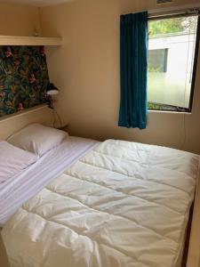 ein weißes Bett in einem Zimmer mit Fenster in der Unterkunft Stacaravan huren in het hart van bosrijk Drenthe op Recreatiepark De Tien Heugten in Schoonloo + 11 Fotos