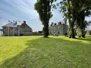 un grand bâtiment en pierre avec deux drapeaux dans l'herbe dans l'établissement La Salmonière, au Vivier-sur-Mer