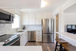 a kitchen with white cabinets and a stainless steel refrigerator at Steps to the beach upstairs Apartment with 3 bedrooms & 2 bath AC in Kailua
