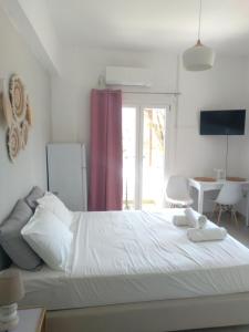 a bedroom with a large white bed with a window at IOKASTI STUDIOS in Andros