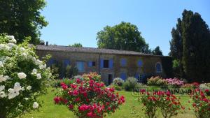 een oud stenen huis met bloemen in de tuin bij La Chapelle Gite avec piscine chauffee in Valréas