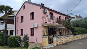 een roze huis met een balkon aan een muur bij Apartment Nela in Funtana