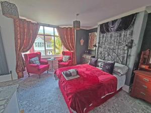 a bedroom with a red bed and a red chair at The Miggi vegan guesthouse in Torquay