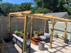 a patio with a wooden pergola and two benches at The Old Mill in Lymington