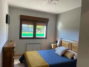 sypialnia z niebieskim łóżkiem i oknem w obiekcie CAMPOS DE BALEA (1ªPLANTA) w mieście O Grove