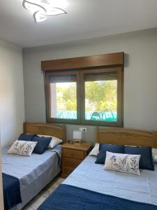 a bedroom with two beds and two windows at CAMPOS DE BALEA (1ªPLANTA) in O Grove