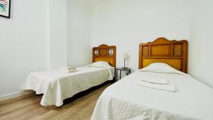 2 Betten in einem Zimmer mit weißen Wänden und Holzböden in der Unterkunft Suite Dream Capricho in Vecindario