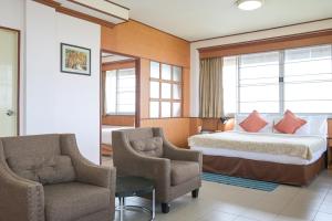 a hotel room with a bed and two chairs at Rattana Park Hotel in Phitsanulok