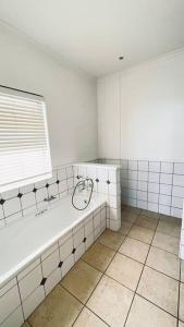 a white bathroom with a tub and a window at Luxury Lodge at Pinnacle Point in Mossel Bay