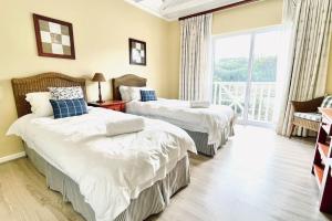 two beds in a hotel room with a balcony at Luxury Lodge at Pinnacle Point in Mossel Bay