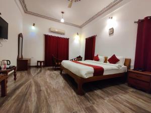 a bedroom with a large bed with red curtains at Satyam Palace- Heritage Luxury Resort in Pushkar