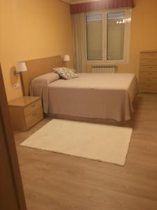 a bedroom with two beds and a window and a rug at paseo de la Quinta in Colindres