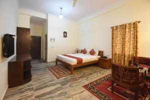 a bedroom with a bed and a tv and a couch at Satyam Palace Resort in Pushkar