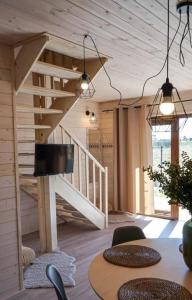 a room with a wooden staircase and a table with chairs at Domki Krasne Morze in Mielenko