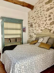 um quarto com uma cama e uma parede de pedra em La Posada em Pézenas