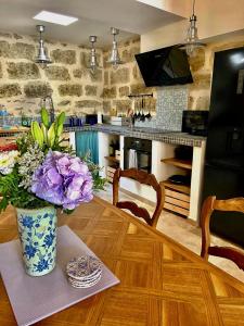 uma cozinha com uma mesa com um vaso de flores roxas em La Posada em Pézenas