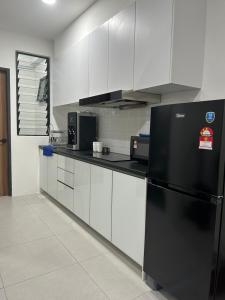 a kitchen with a black refrigerator and white cabinets at Armadale Residence-Gala City in Kuching