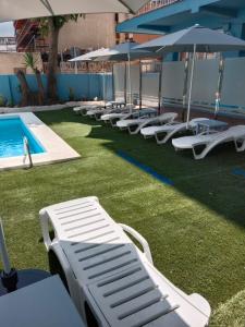 een rij ligstoelen en parasols naast een zwembad bij Apartamentos El Velero in Torremolinos