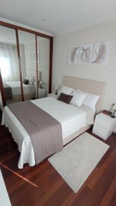 ein Schlafzimmer mit einem großen weißen Bett und einem Spiegel in der Unterkunft Val do Fragoso in Vigo