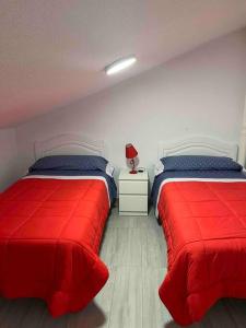 a bedroom with two beds with red sheets and a lamp at CASA EN ISLA DE TABARCA (ZONA PUERTO VIEJO) in Tabarca