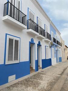 - un bâtiment bleu et blanc avec balcon dans une rue dans l'établissement CASA EN ISLA DE TABARCA (ZONA PUERTO VIEJO), à Tabarca