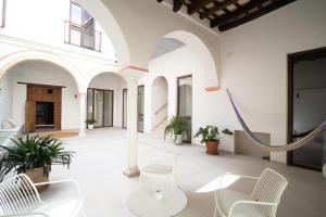 サンルーカル・デ・バラメダにあるApartamentos Alcoba 13の白い椅子とハンモック付きの広い客室です。