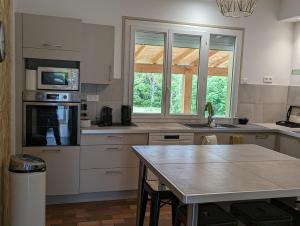 eine Küche mit weißen Schränken und einem Tisch darin in der Unterkunft La Fontaine in Montgaillard-Lauragais