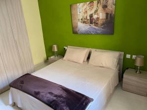 1 dormitorio con cama blanca y pared verde en Sunset Apt Modern 1 bedroom Apt near the Beach en Birżebbuġa