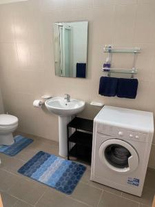 a bathroom with a washing machine and a sink at Sunset Apt Modern 1 bedroom Apt near the Beach in Birżebbuġa